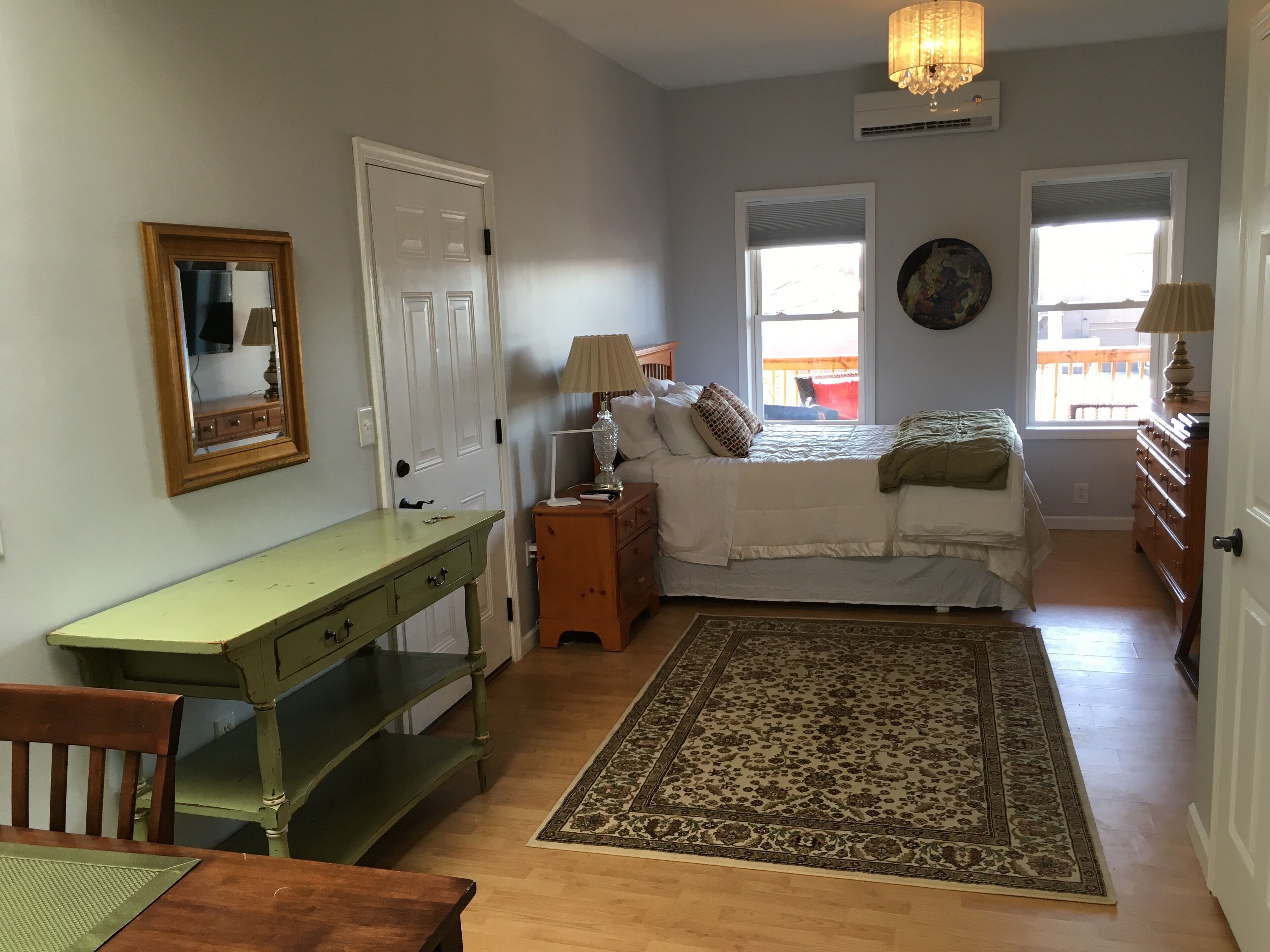 A bedroom with a bed, bedside tables, a desk, a chair, a rug, and a window.