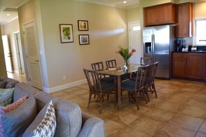 A dining area with a table and chairs, a refrigerator, and wooden cabinets.