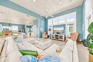 A spacious living room with a large TV, comfortable seating, and a ceiling fan.