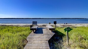 A wooden boardwalk leading to a beach with a sign indicating lights are off from 10 PM to 6 AM and red flags on the beach. - 9 Lands End Rd-Pretty view, Pool Onsite, Easy Walk to water & S. Beach Marina (Hilton Head Island)