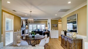 A spacious dining area with a marble table, white chairs, and a chandelier. - 9 Lands End Rd-Pretty view, Pool Onsite, Easy Walk to water & S. Beach Marina (Hilton Head Island)