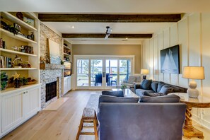 Relax in this inviting living area with a high ceiling, fireplace, and sliding glass door leading to an outdoor patio.