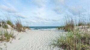 A sandy beach with dunes and grass in the foreground, leading to the ocean. - 442 Captains Walk | Direct Oceanfront Views (Hilton Head Island)