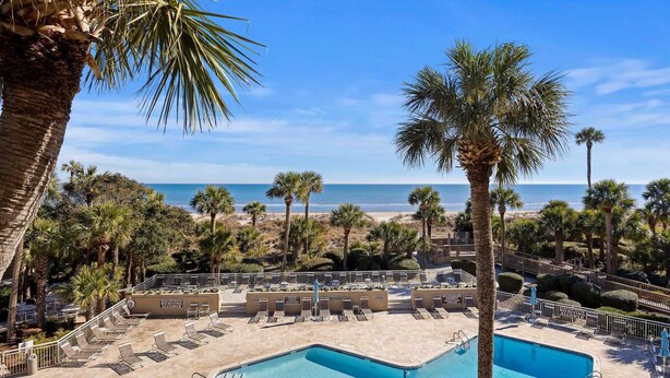 A pool area with lounge chairs and a view of the beach. - 442 Captains Walk | Direct Oceanfront Views (Hilton Head Island)