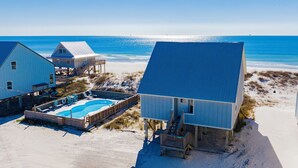 A beachfront property with a swimming pool, beach houses, and a wooden deck.