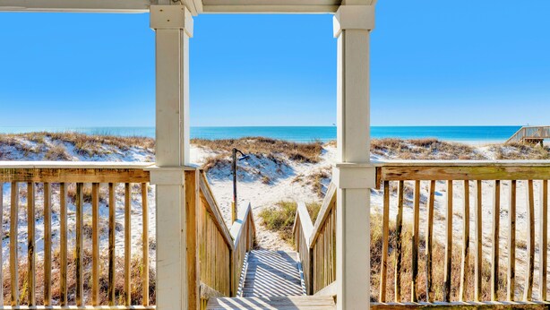 A wooden staircase leading to a beach with a clear blue sky.