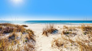 A beach with sand dunes and a clear blue sky.