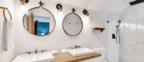 Un baño moderno con dos lavamanos, inodoro y ducha.