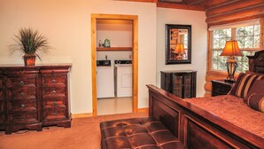A bedroom with a wooden headboard, a large bed, a dresser, a mirror, and a window with a lamp. - River Tranquility managed by Cabin Butler (Greer)