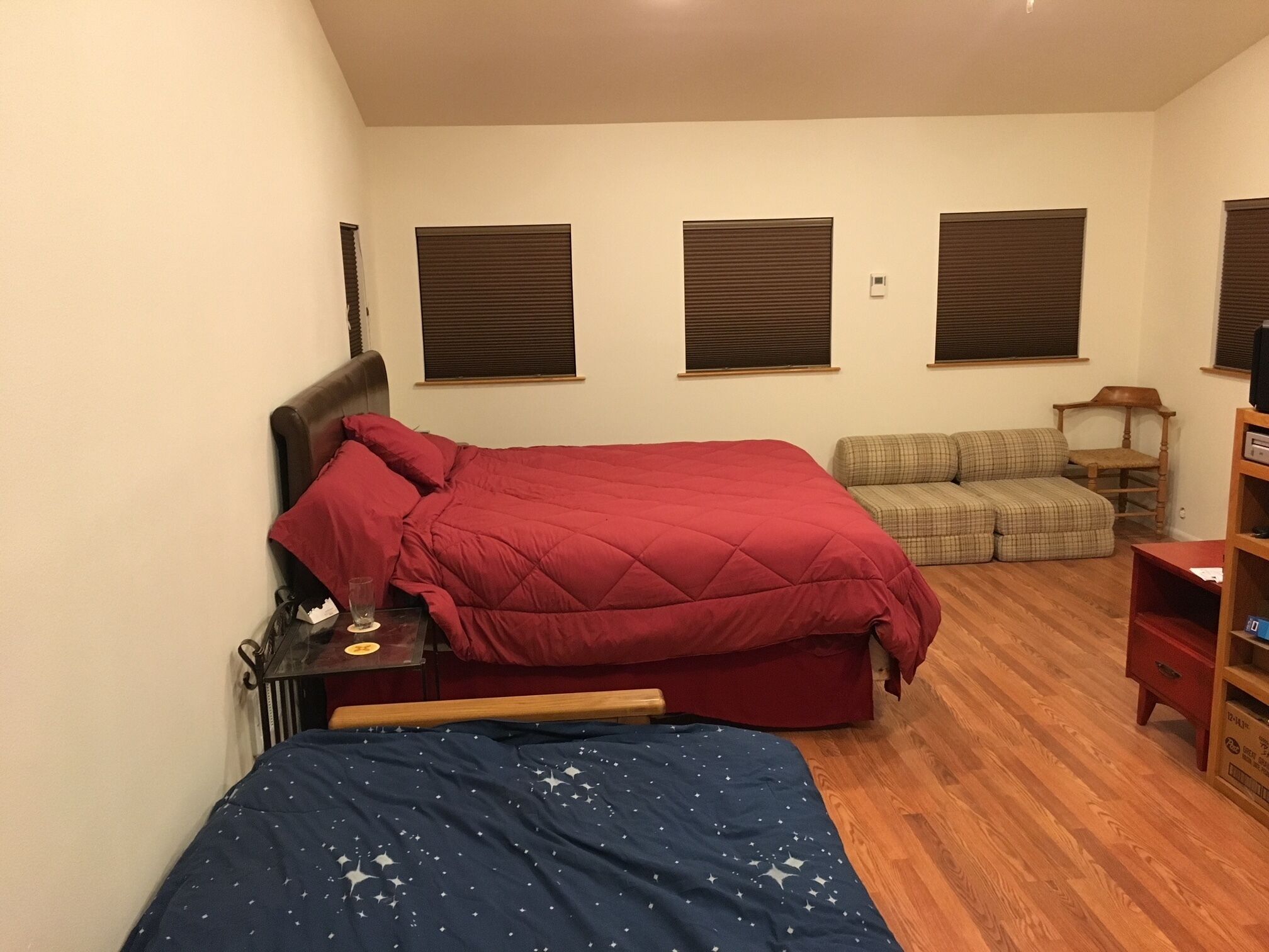 Une chambre à coucher avec un lit, un canapé, un plancher en bois et une table de chevet.