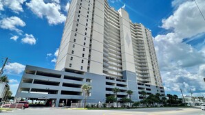 A multi-story parking garage adjacent to a tall residential building with balconies. - Platinum Rated, Beach Front, Condo at Ocean Reef with Free Beach Chairs! (Panama City Beach)