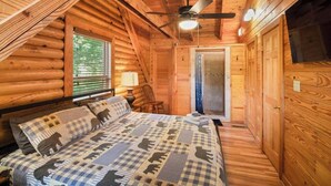 Une chambre confortable dans un chalet en rondins, avec un lit, un ventilateur de plafond et une fenêtre.