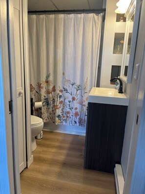 Ein Badezimmer mit Toilette, Waschbecken und einer Duschvorhang mit Blumenmuster.