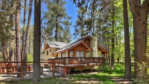 A cabin with a deck, surrounded by tall trees.