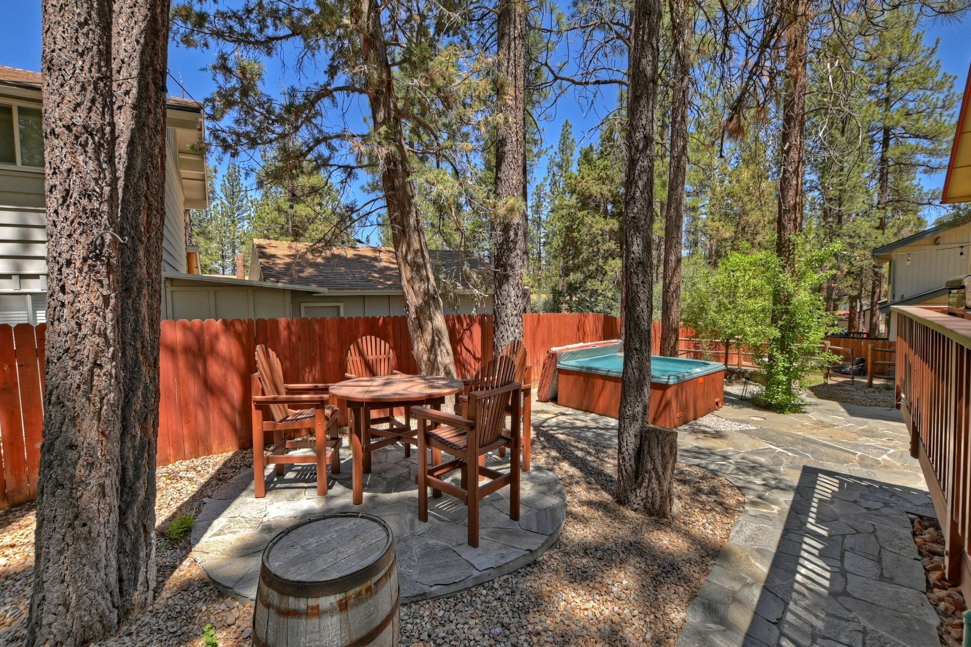 Un patio trasero con una mesa y sillas de madera, un jacuzzi y una piscina pequeña.