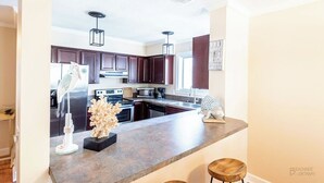 A modern kitchen with dark wood cabinets, stainless steel appliances, and a granite countertop.