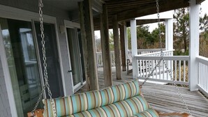A wooden porch with a swing seat featuring striped cushions. - Let yourself be "Swept Away"  BOOK OUR BEAUTIFUL HOME NOW FOR 2026 (Corolla)