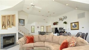 A spacious living room with a curved sofa, a glass coffee table, and a fireplace. - Let yourself be "Swept Away"  BOOK OUR BEAUTIFUL HOME NOW FOR 2026 (Corolla)