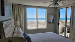 A bedroom with a bed, a ceiling fan, a window with a beach view, and a balcony with a chair. - Breathtaking views directly facing the Gulf!  3bd/3bath/6 (Fort Walton Beach)