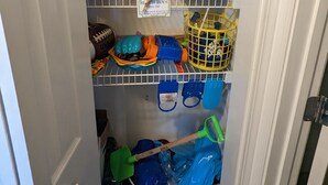 A storage area with shelves holding various beach toys, including buckets, shovels, and toys. - Breathtaking views directly facing the Gulf!  3bd/3bath/6 (Fort Walton Beach)