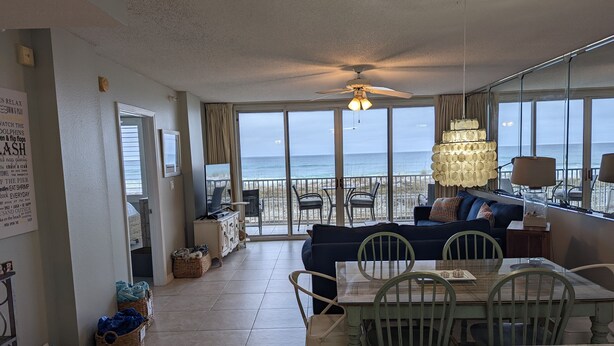 A spacious living room with a large window overlooking the beach, a ceiling fan, and a dining area with a table and chairs. - Breathtaking views directly facing the Gulf!  3bd/3bath/6 (Fort Walton Beach)