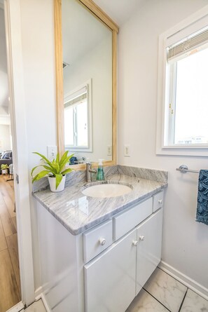A bathroom with a marble sink, a potted plant, and a large mirror. - Best View and Amenities on the Island. Stay & Play (Wrightsville Beach)