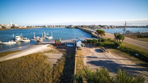 A marina with boats docked, a pier extending into the water, and a road alongside.