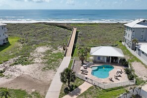 Una propiedad frente a la playa con piscina, un patio cubierto y un muelle que da al océano.