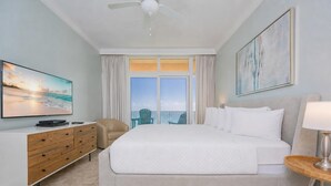 Habitación de hotel con cama, televisión, escritorio, silla, lámpara y un cuadro.
