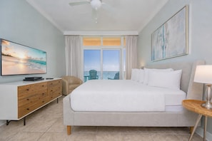 A hotel room with a bed, a TV, a desk, a chair, a lamp, and a painting.