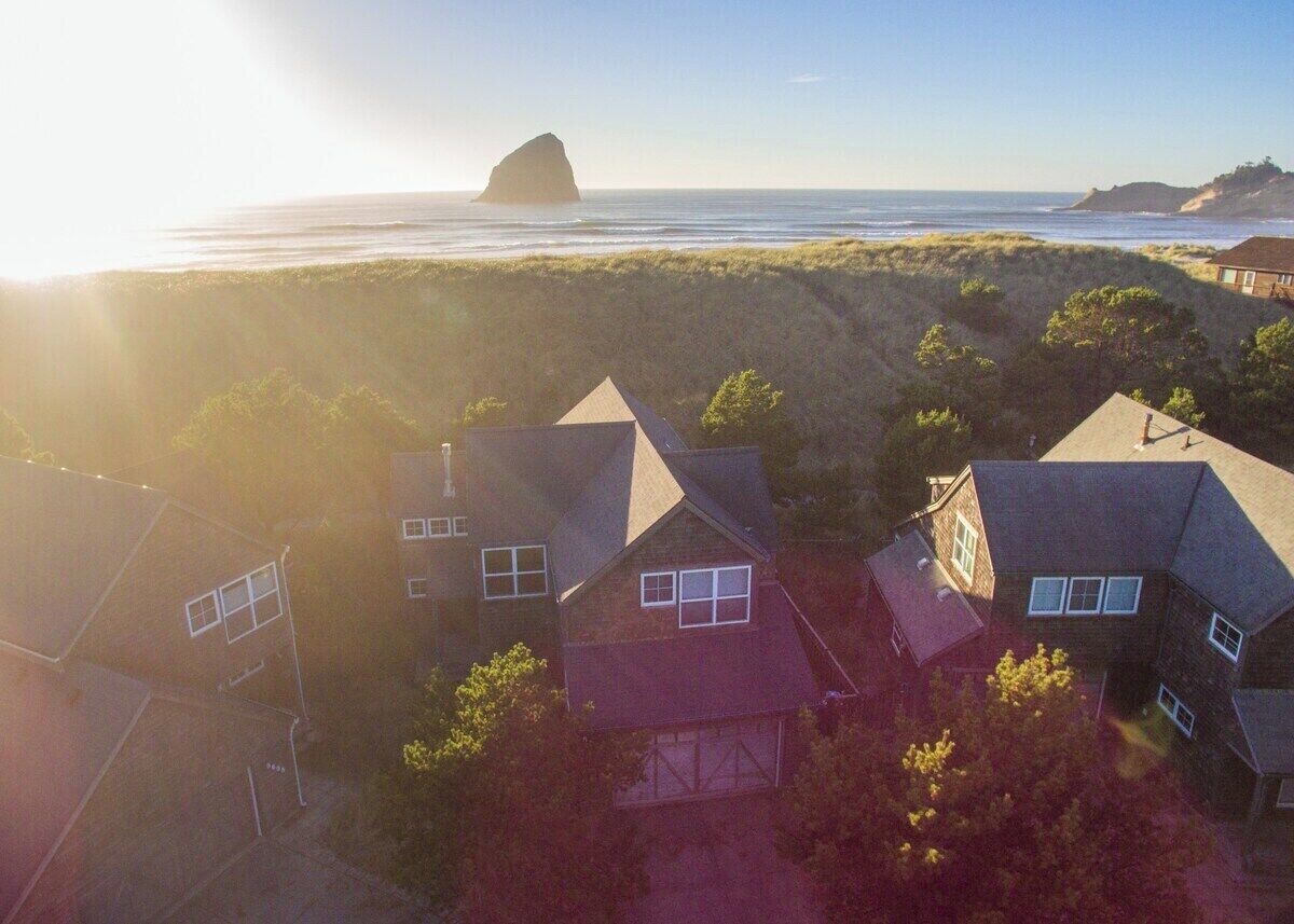 A coastal residential area with houses, a beach, and a prominent rock formation in the distance.