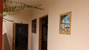 Un pasillo con suelo de baldosas, una puerta de madera y un cuadro colgado en la pared.