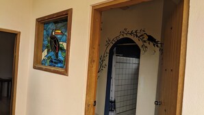 Un pasillo con una puerta de madera que da a un cuarto con baldosas, una ventana con vitrales y un arco decorativo.