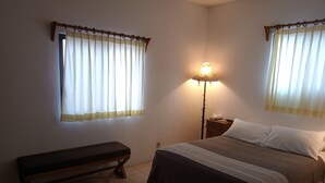 Un dormitorio con una cama, una mesita de noche, una lámpara y un banco.