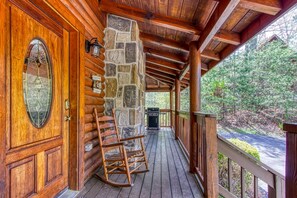 A wooden log cabin with a stone wall, a rocking chair, and a grill on the porch. - ER92 - Virginia's Villa - Great location! Close to all the action! (Pigeon Forge)