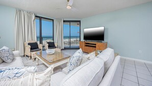 A living room with a sofa, two armchairs, a coffee table, and a TV on a wooden stand.