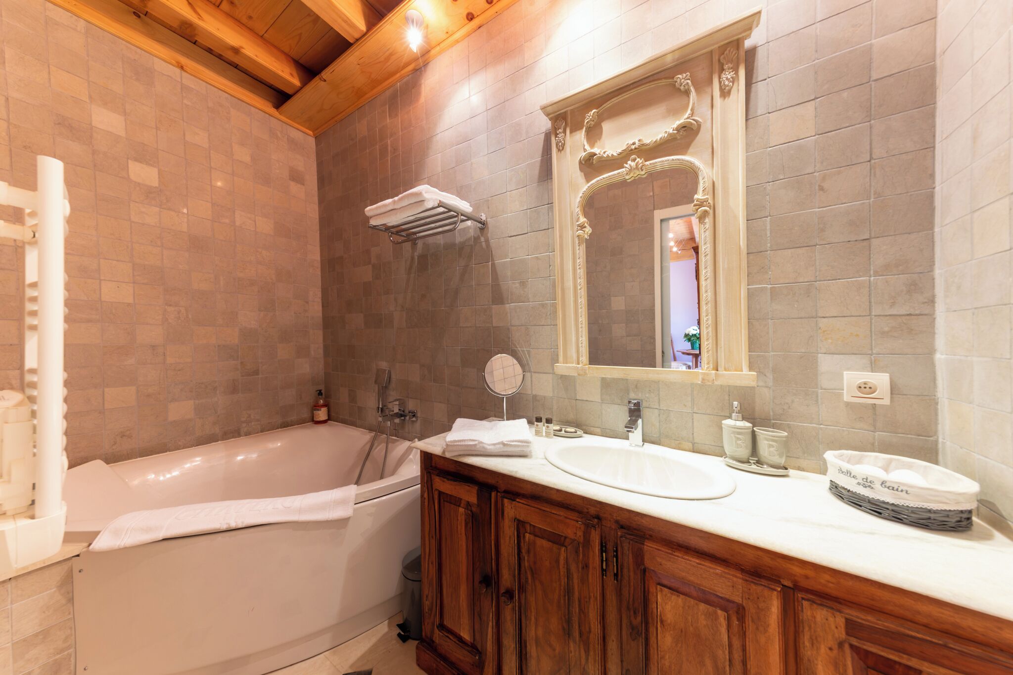 A bathroom with a bathtub, a sink, a vanity with cabinets, a mirror, and a towel rack.