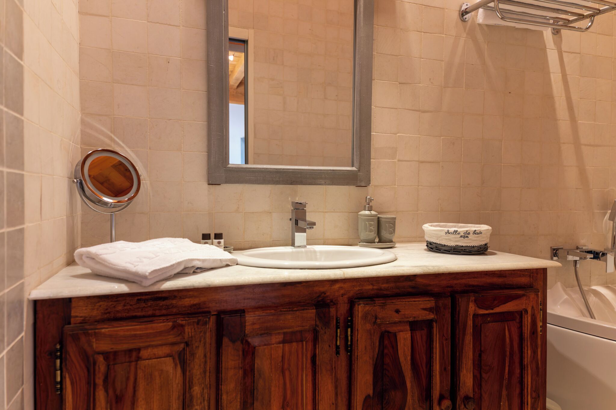 A bathroom with a sink, mirror, and bathtub.