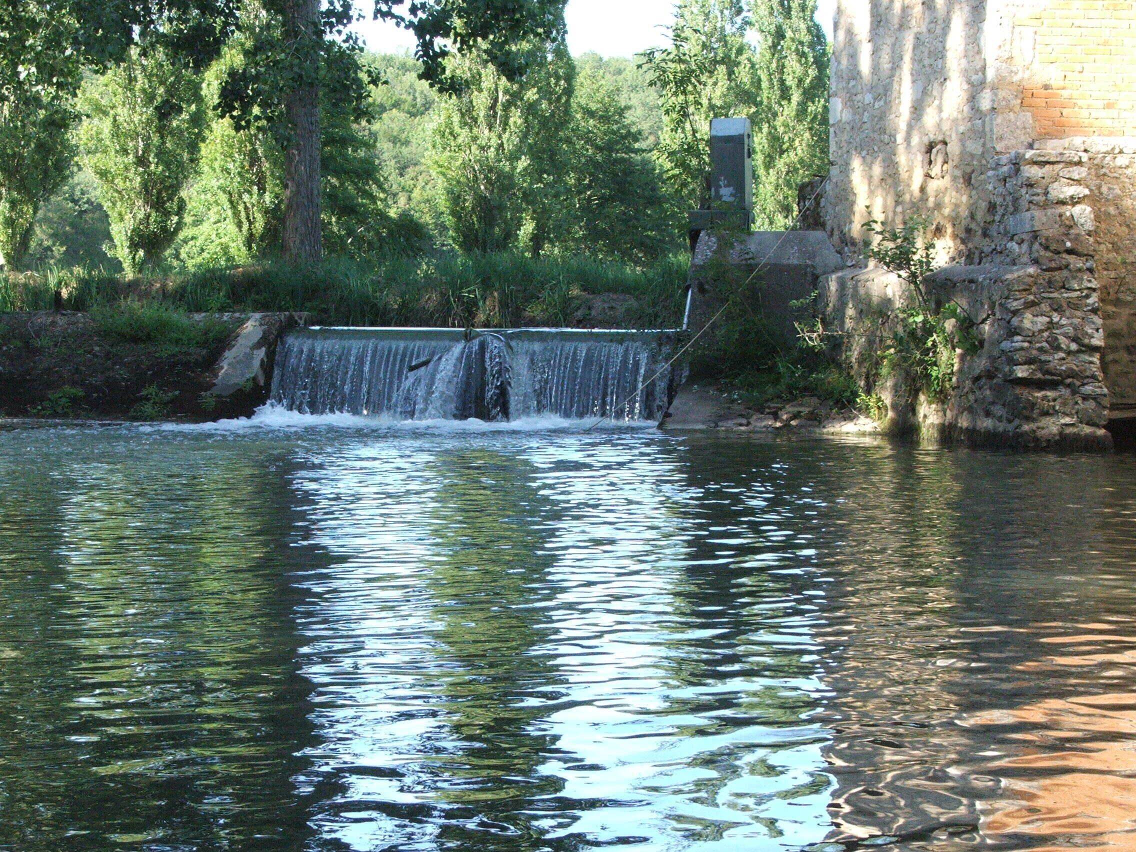 A waterfall in a natural setting with stone walls and trees.