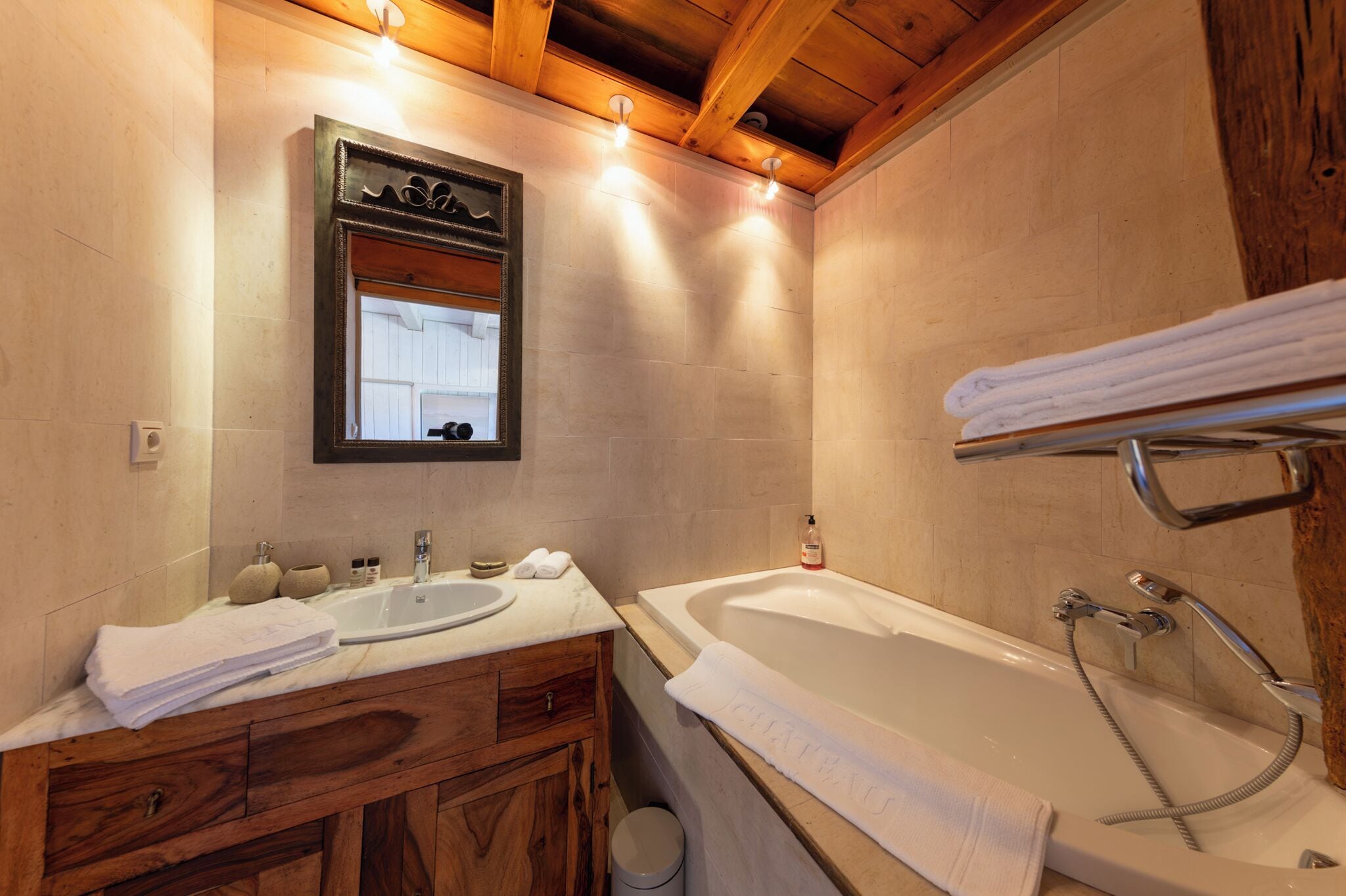 Une salle de bain avec un meuble-lavabo en bois, un lavabo, une baignoire et un miroir.