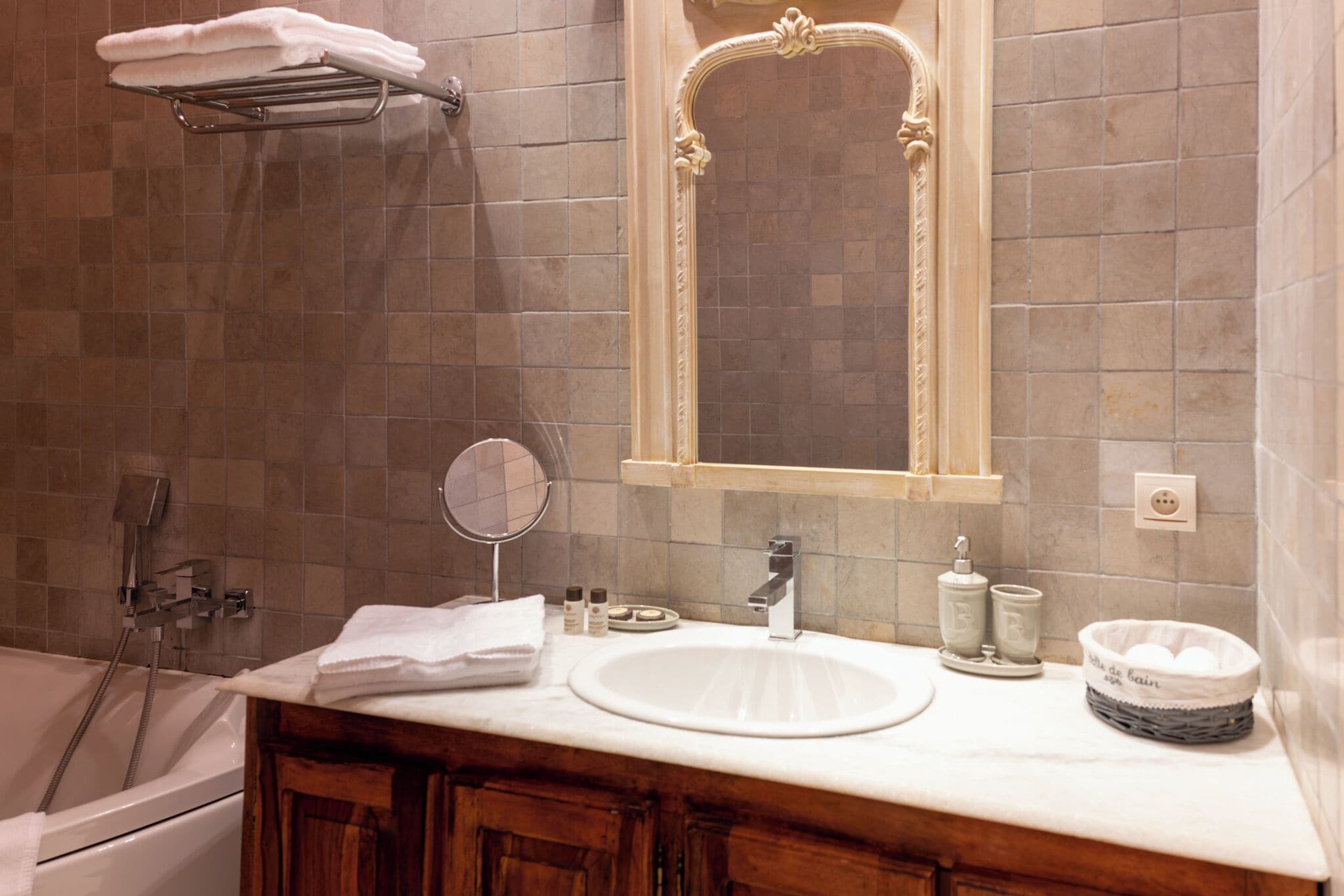 A bathroom with a bathtub, a sink, a mirror, and a towel rack.