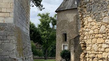 Un bâtiment en pierre doté d’une tour, entouré d’une zone herbeuse et d’arbres.