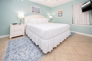 A bedroom with a bed, nightstands, a TV, and artwork on the walls.