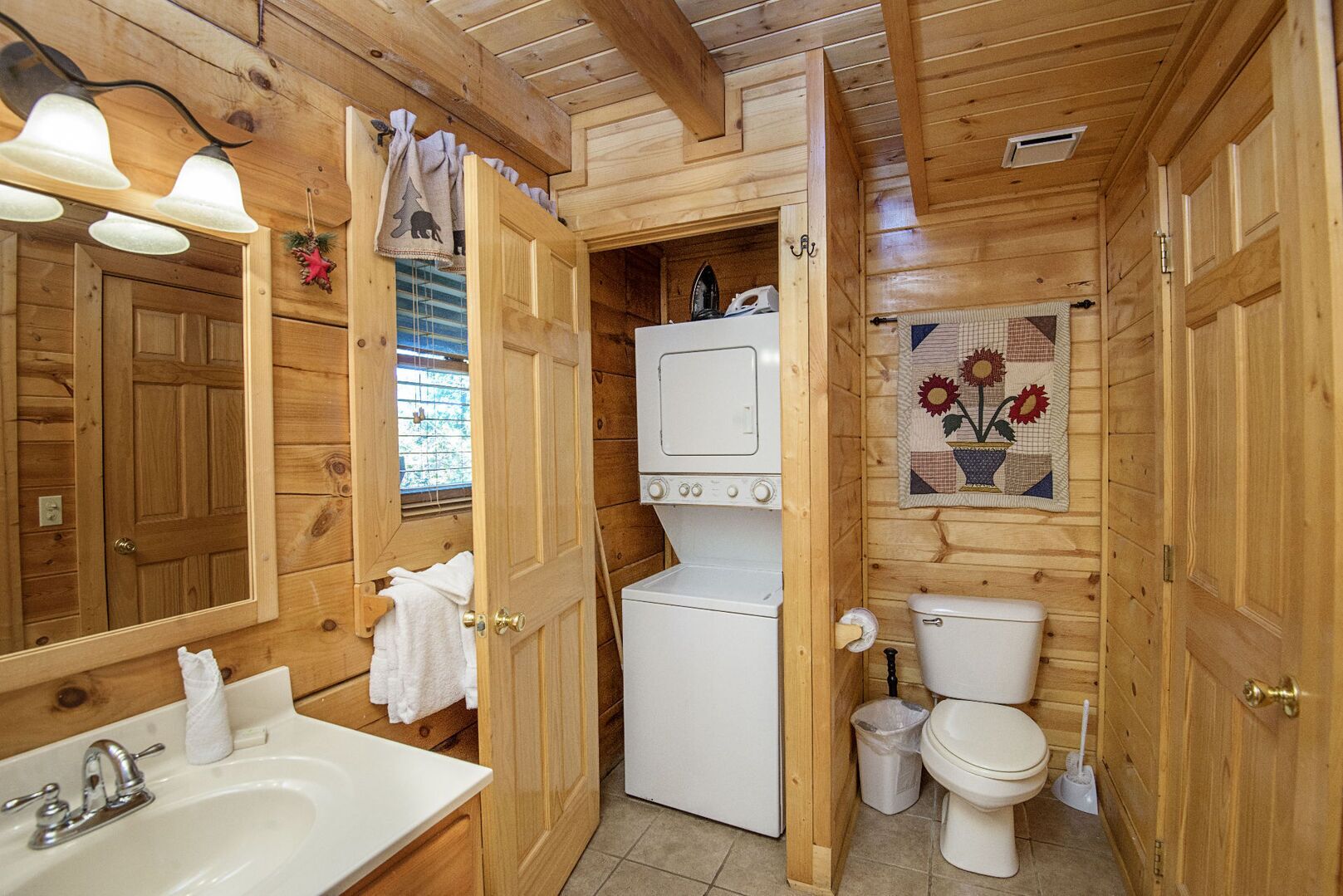 A wooden cabin bathroom with a sink, toilet, and washing machine.