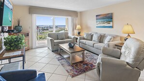 A living room with a sofa set, a coffee table, and a TV. There is a view of the ocean through the windows. - Coastal Comfort & Resort Fun – Islander 613 (Destin)