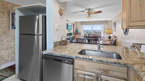A modern kitchen with granite countertops, stainless steel appliances, and a view to the living area. - Coastal Comfort & Resort Fun – Islander 613 (Destin)