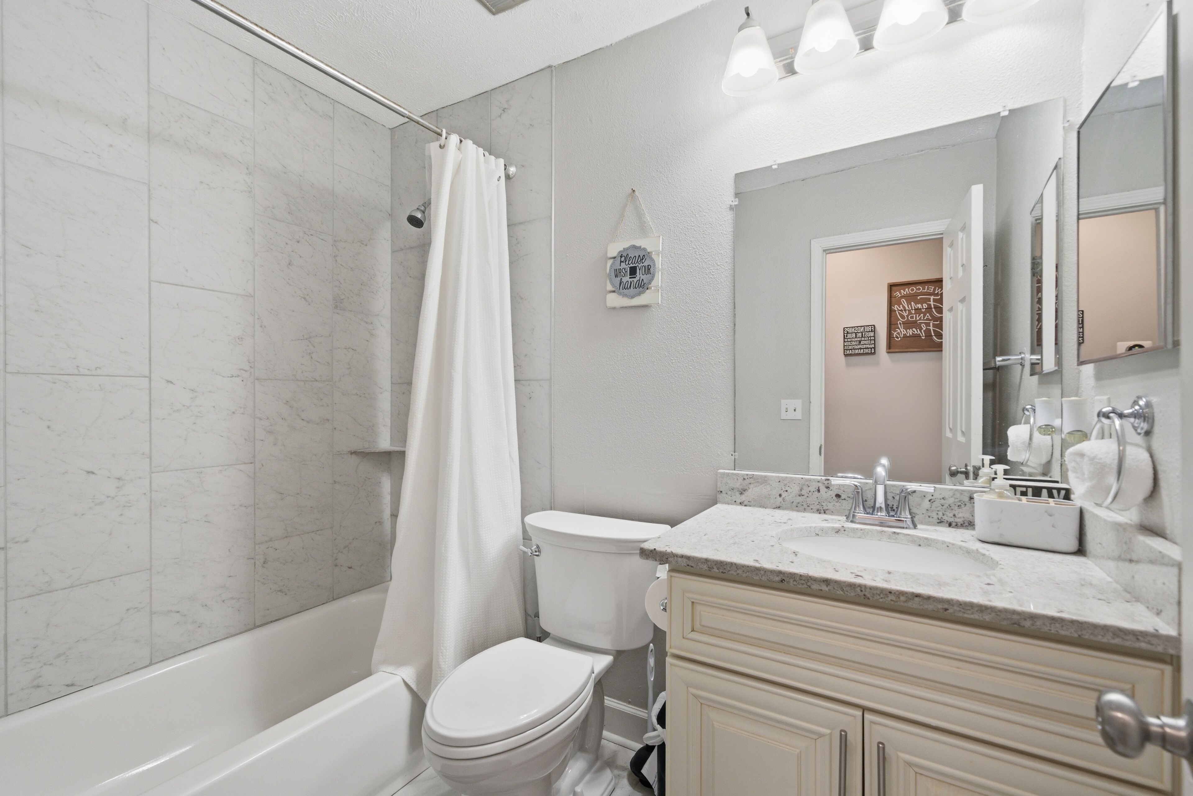 A bathroom with a shower, toilet, sink, and vanity.