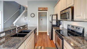 A kitchen with granite countertops, stainless steel appliances, and a wooden floor.