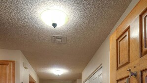 Un couloir avec des portes en bois, un sol carrelé et un luminaire au plafond.