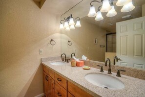 Een badkamer met twee wastafels, houten kastjes, een spiegel en een plafondlamp.